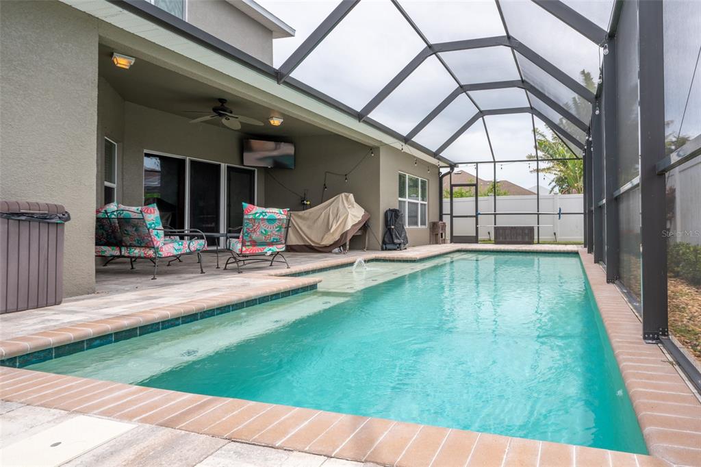 A screened-in patio features a rectangular swimming pool with a tanning ledge and brick coping — 1809 BONITA BLUFF COURT, RUSKIN, FL