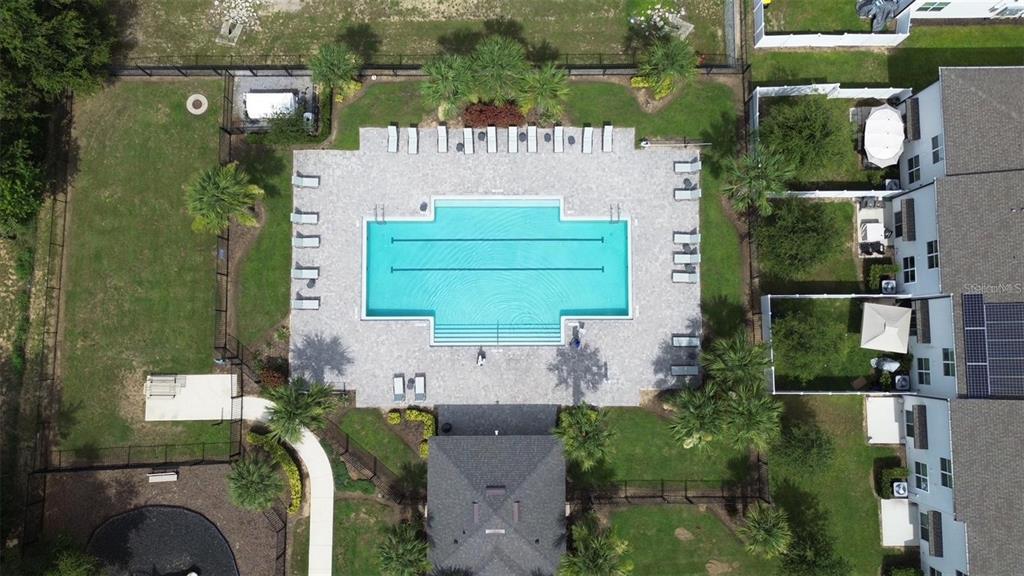 An aerial view shows a rectangular swimming pool with lap lanes surrounded by a paved deck — 645 MADISON DRIVE, DAVENPORT, FL