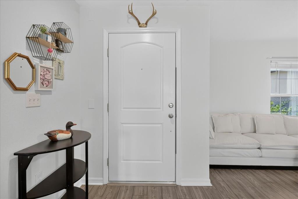 An entryway features a white door, a small dark table, and wall-mounted geometric shelves — 26 ROCKINGHAM LANE, PALM COAST, FL