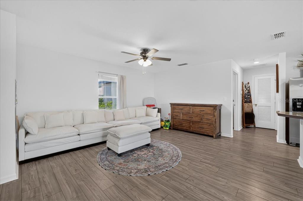 A living room features a white sectional sofa, a wooden dresser, and wood-look flooring — 26 ROCKINGHAM LANE, PALM COAST, FL