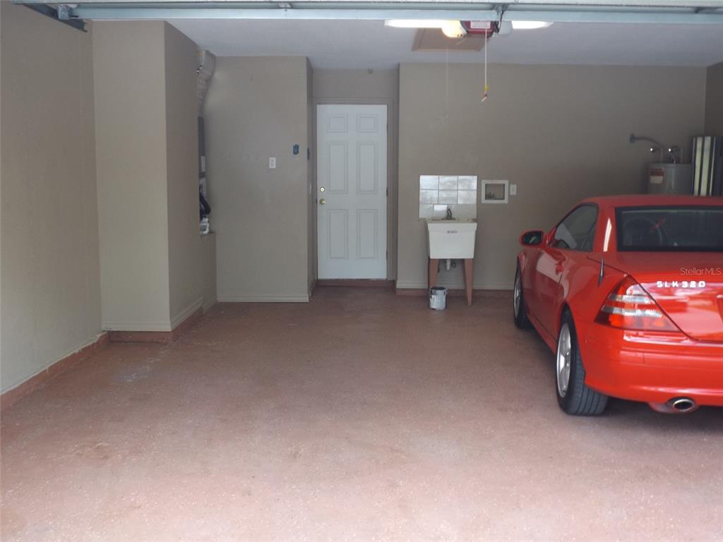 A garage with a concrete floor, a utility sink, and a red car parked inside — 9 BOWMAN PLACE, PALM COAST, FL