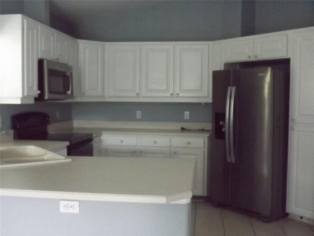 A kitchen with white cabinets, stainless steel appliances, and light-colored countertops — 9 BOWMAN PLACE, PALM COAST, FL