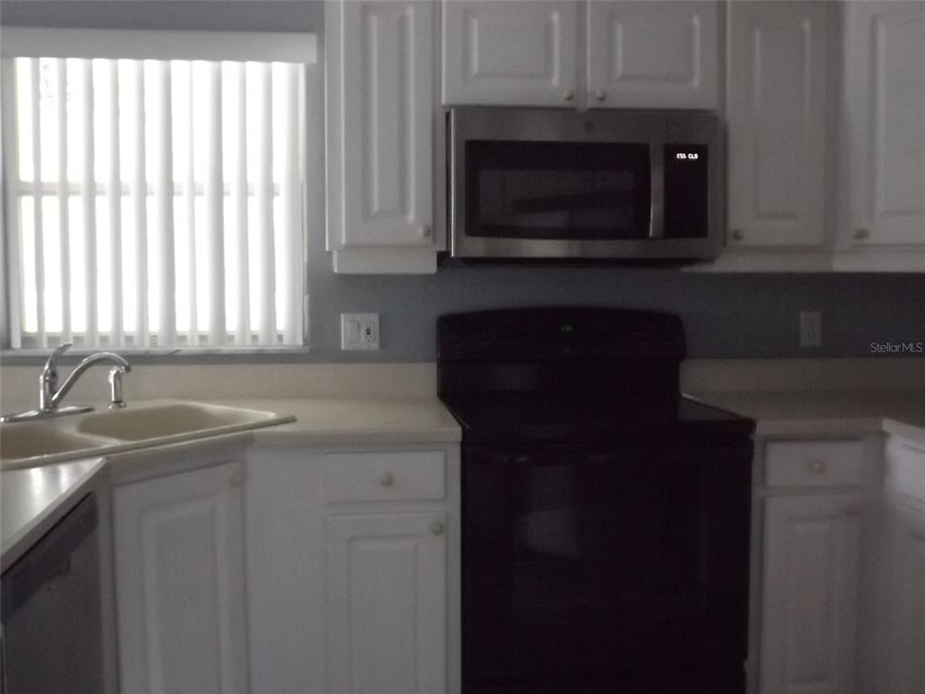 A kitchen features white cabinets, a stainless steel microwave, and a black stove — 9 BOWMAN PLACE, PALM COAST, FL