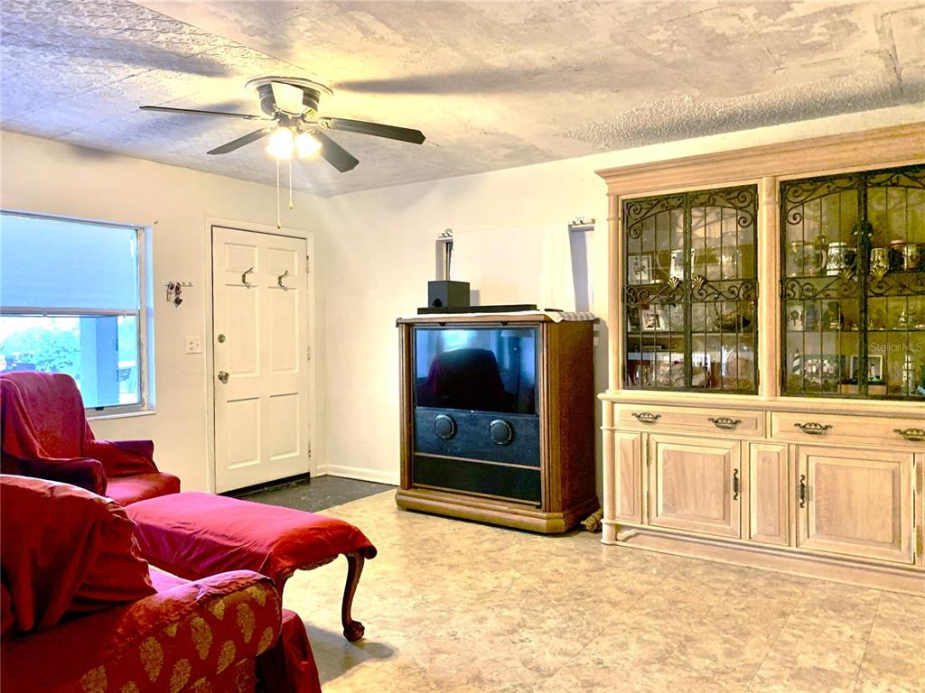 A living room features a red armchair, a television console, and a large wooden hutch — 701 S DELAWARE AVENUE, DELAND, FL
