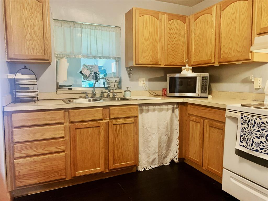 A kitchen with light wood cabinets, a double sink, and a white stove — 701 S DELAWARE AVENUE, DELAND, FL