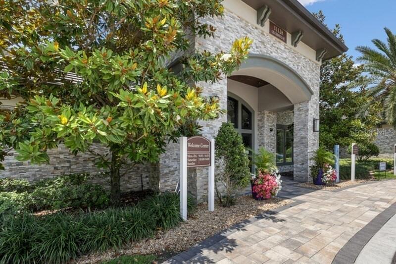A stone-faced building entrance features a welcome center sign, a large tree, and paved walkway — 11128 GRANDE PINES CIRCLE UNIT Mirage, ORLANDO, FL