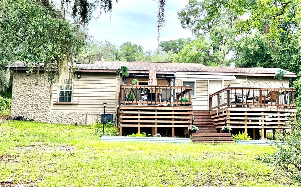 A single-story house with tan siding, stone accents, and a large wooden deck — 208 ASHLEY STREET, HAWTHORNE, FL
