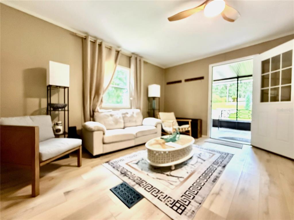 A living room features light wood flooring, a white sofa, and a glass-topped coffee table — 208 ASHLEY STREET, HAWTHORNE, FL