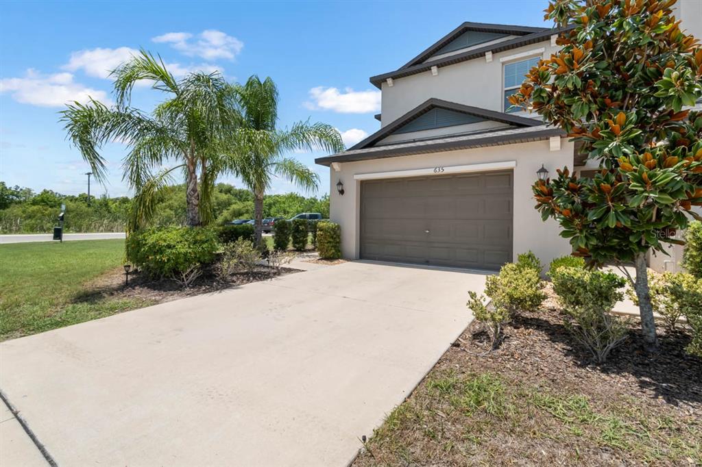A two-story house exterior features a concrete driveway, a garage, and a palm tree — 635 ROYAL EMPRESS DRIVE, RUSKIN, FL