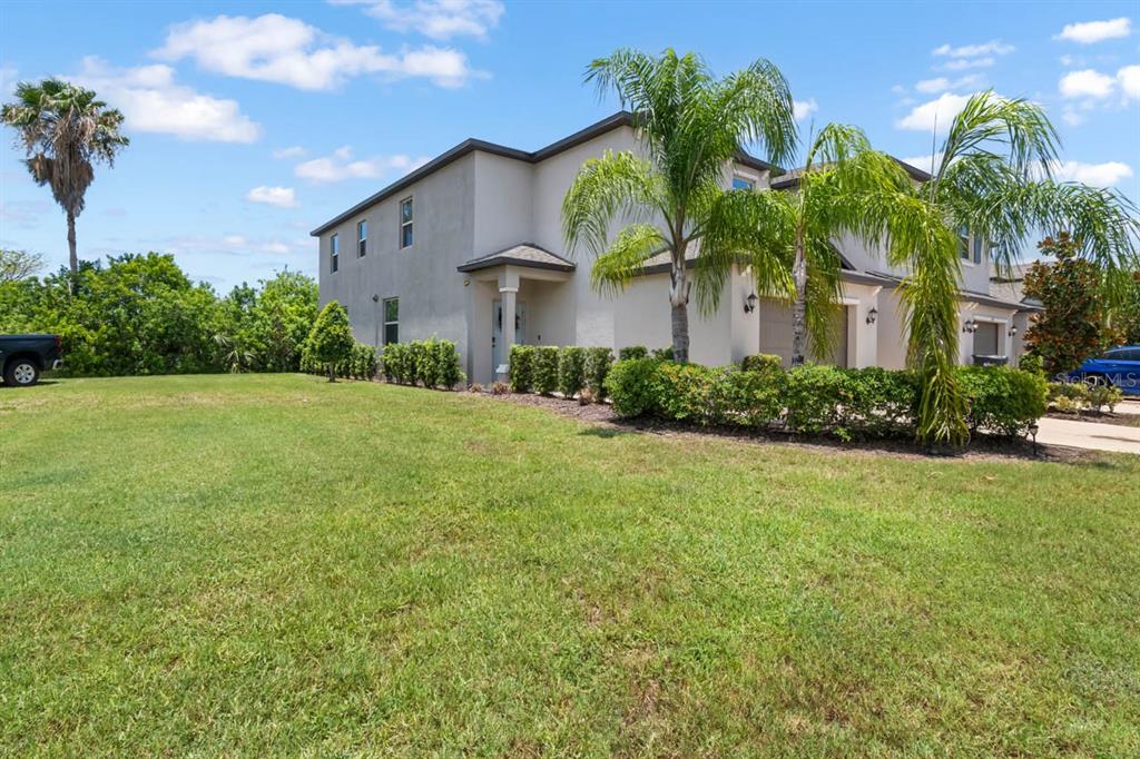 A two-story townhouse with a beige stucco exterior, a small front porch, and palm trees — 635 ROYAL EMPRESS DRIVE, RUSKIN, FL
