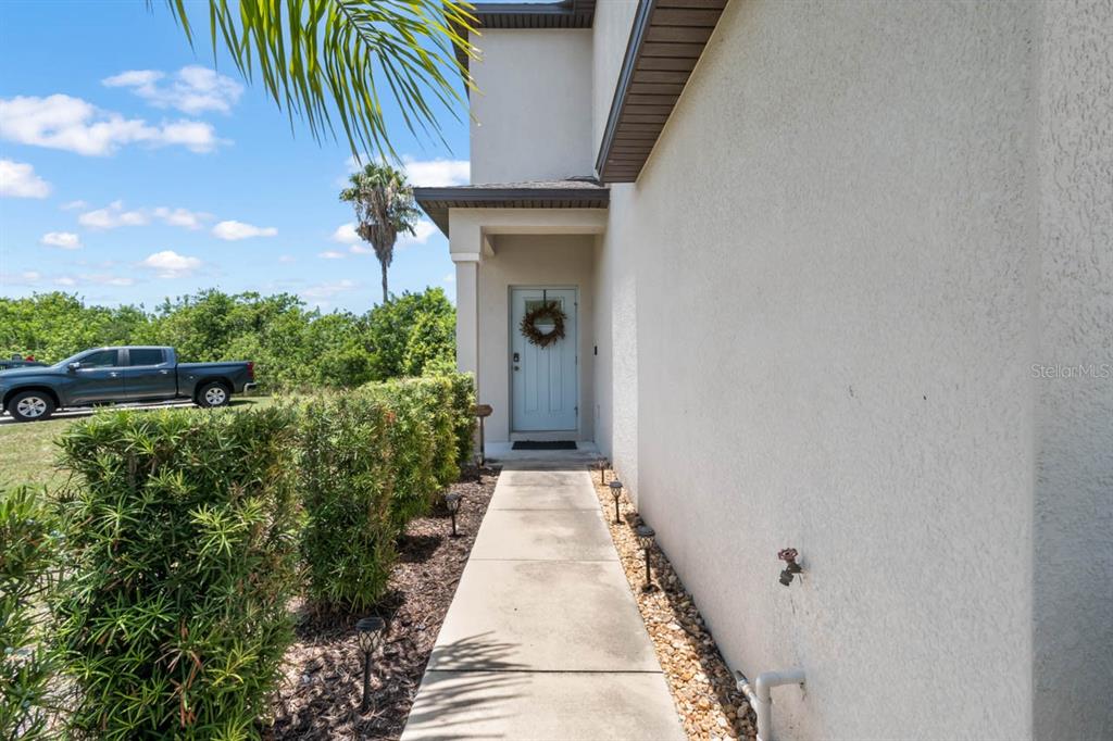 A concrete walkway leads to the light blue front door of a stucco house — 635 ROYAL EMPRESS DRIVE, RUSKIN, FL