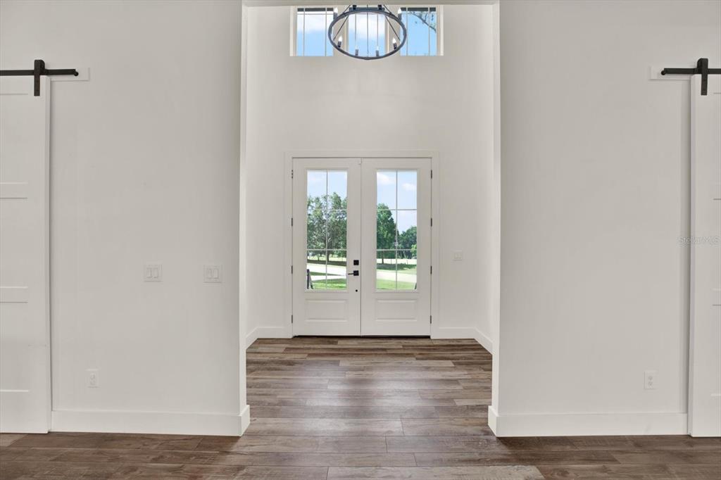 An entryway features white walls, wood-look flooring, a double-door entrance, and a high ceiling — 35940 RAMSEY RIDGE DRIVE, DADE CITY, FL