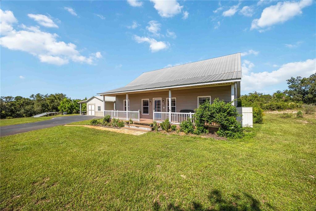 A single-story house with a metal roof and a front porch sits on a lawn — 2711 SNYDER ROAD, SEBRING, FL