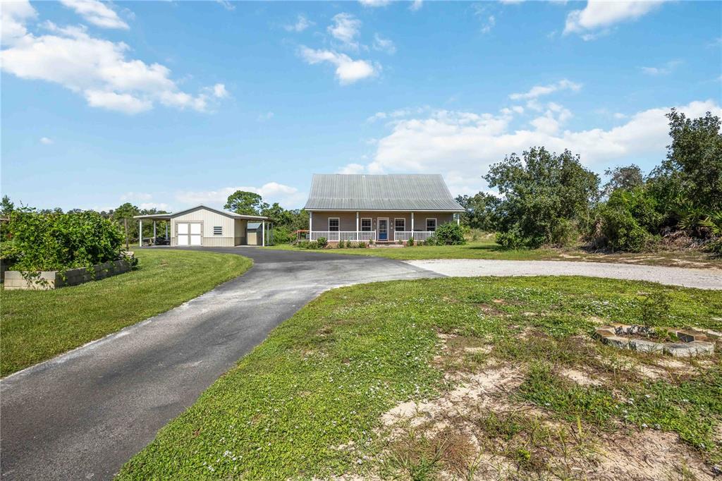 A house with a metal roof and a detached garage sits at the end of a driveway — 2711 SNYDER ROAD, SEBRING, FL