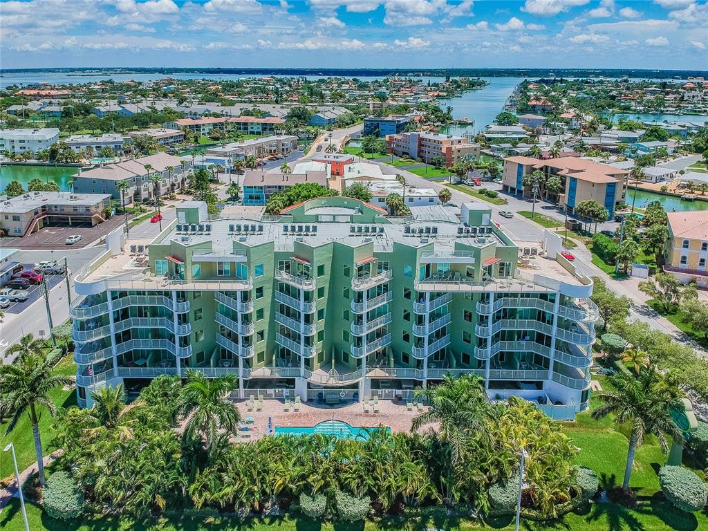 An aerial view of a multi-story green apartment building with a swimming pool and landscaping — 11605 GULF BOULEVARD UNIT 402, TREASURE ISLAND, FL