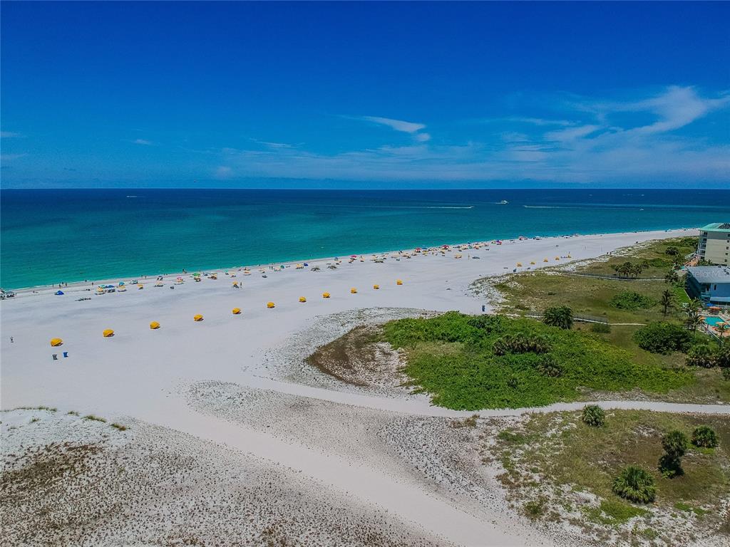 An aerial view of a white sand beach with umbrellas and the ocean beyond — 11605 GULF BOULEVARD UNIT 402, TREASURE ISLAND, FL