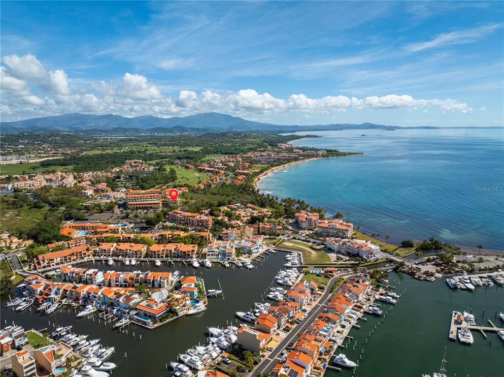 An aerial view shows a coastal resort community with a marina, residential buildings, and mountains — 295 Palmas Inn Way E PALMAS INN WAY PALMANOVA PLAZA UNIT 112,113,114, HUMACAO, PR