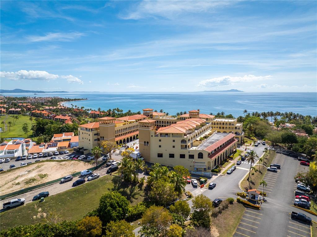 An aerial view of a large, multi-story yellow resort building near the ocean — 295 Palmas Inn Way E PALMAS INN WAY PALMANOVA PLAZA UNIT 112,113,114, HUMACAO, PR