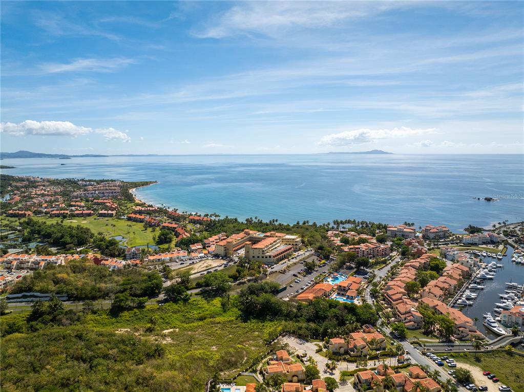 An aerial view shows a coastal resort with a marina, golf course, and ocean horizon — 295 Palmas Inn Way E PALMAS INN WAY PALMANOVA PLAZA UNIT 112,113,114, HUMACAO, PR