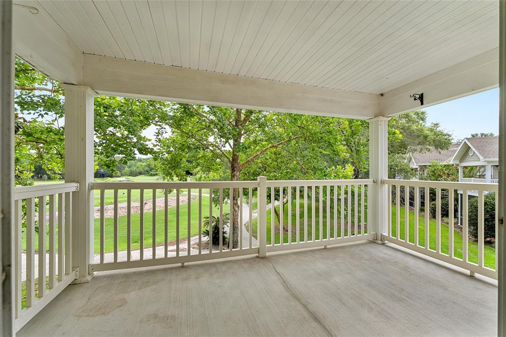 A covered concrete balcony with white railings overlooks a grassy golf course and trees — 10000 SW 52ND AVENUE UNIT 42, GAINESVILLE, FL