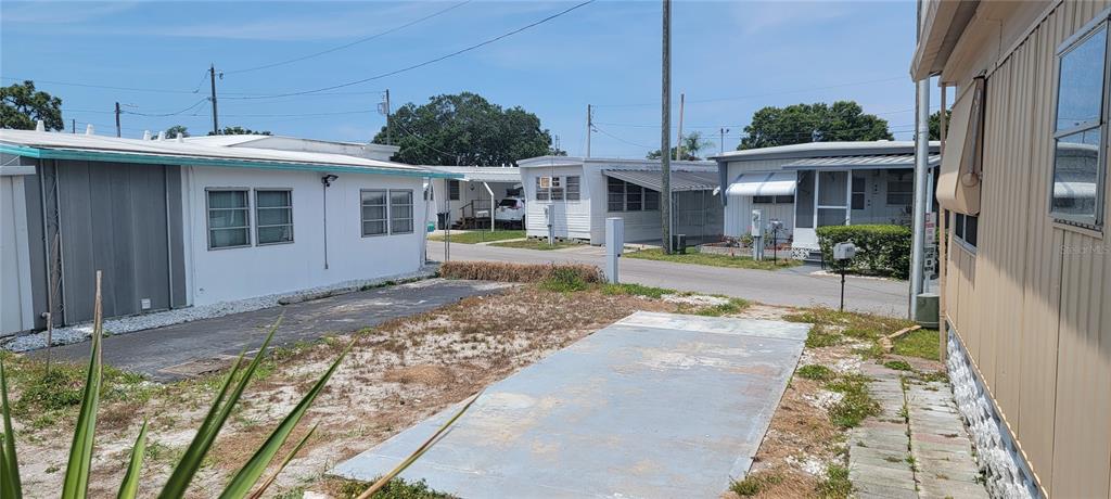 A view of a mobile home exterior with a concrete pad and a gravel driveway — 4715 67TH STREET N UNIT 25, ST PETERSBURG, FL