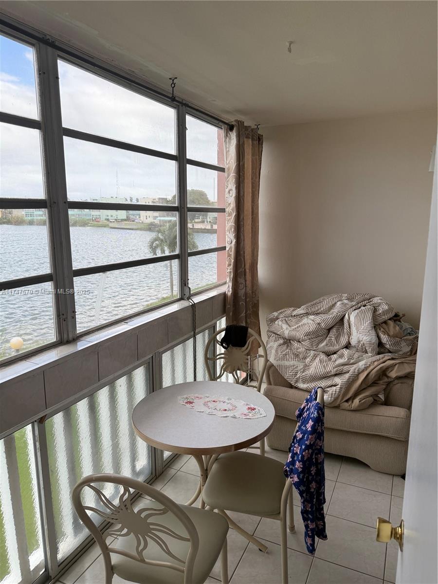 A sunroom features a small dining set, an armchair with bedding, and large windows overlooking water — 18555 NE 14th Ave # 618, Miami FL 33179, MIAMI, FL