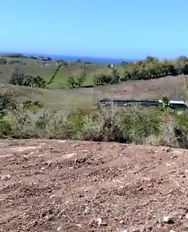 A view of a cleared, rocky lot overlooking rolling green hills and the distant ocean — PR 130 KM 18.0 BO. PUEBLO CUESTA GUAMÁ UNIT Solar 2, HATILLO, PR