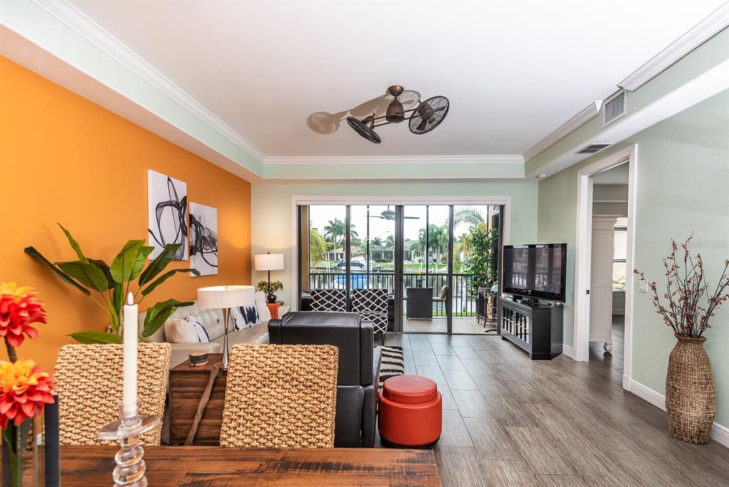 A living room with an orange accent wall, tile flooring, and a view of a canal — 3334 PURPLE MARTIN DRIVE UNIT 212, PUNTA GORDA, FL