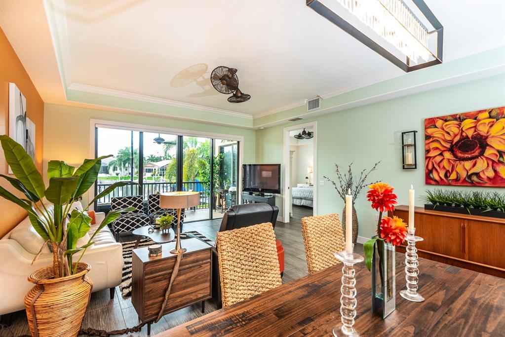 A living and dining area features a wooden table, wicker chairs, and a sliding glass door — 3334 PURPLE MARTIN DRIVE UNIT 212, PUNTA GORDA, FL