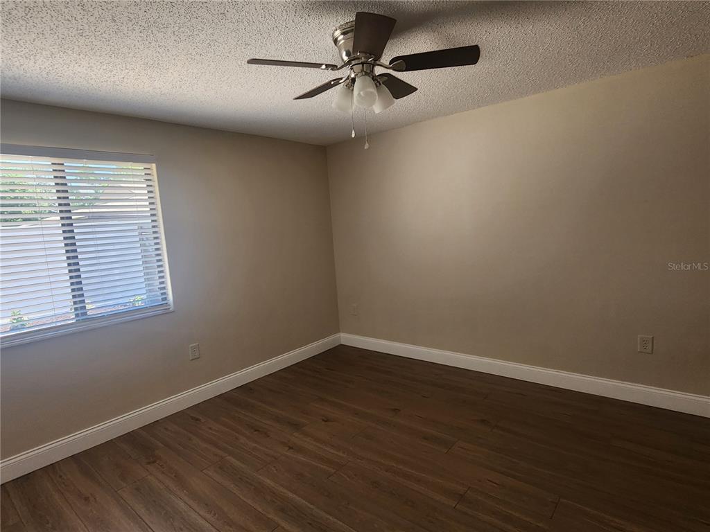 An empty bedroom features light-colored walls, a ceiling fan, and wood-look flooring — 209 CORKWOOD LN, OLDSMAR, FL