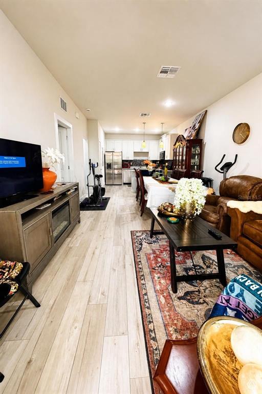 An open-concept living and dining area features light wood-look flooring and a modern kitchen — 1615 CUMIN DRIVE, POINCIANA, FL