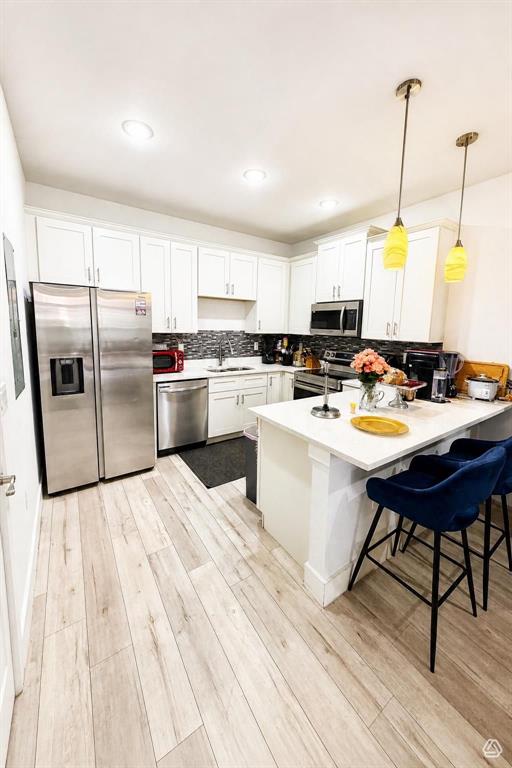 A modern kitchen features white cabinetry, stainless steel appliances, and a central island with stools — 1615 CUMIN DRIVE, POINCIANA, FL