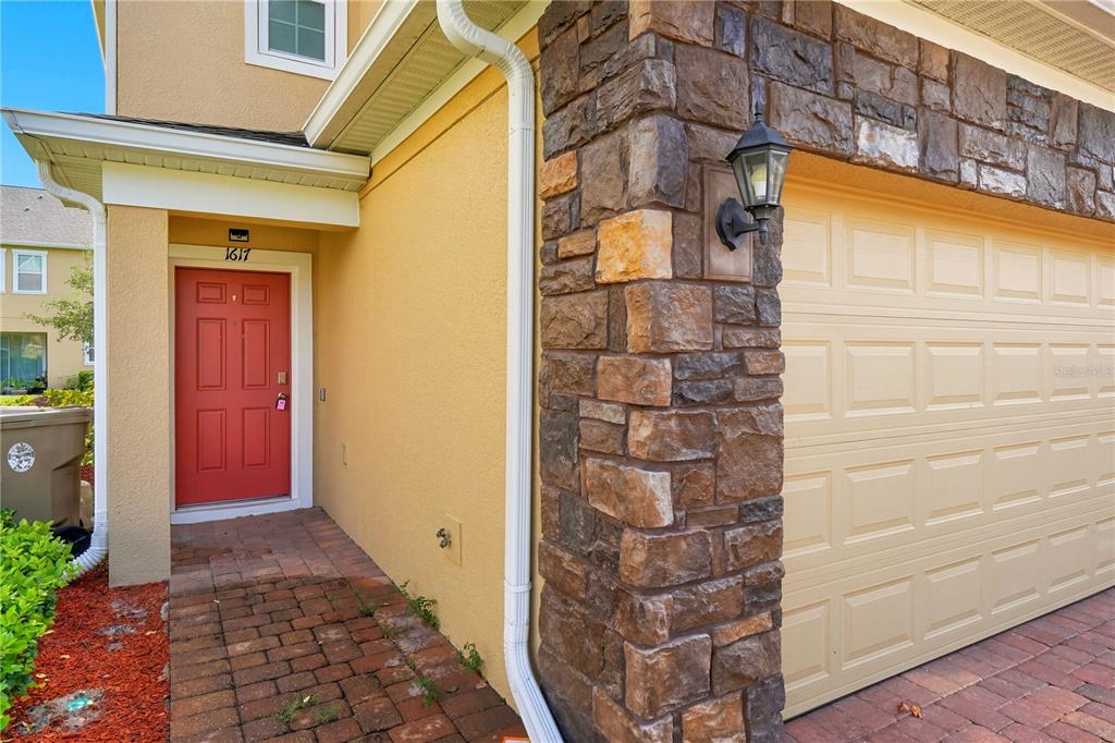 A red front door and a beige garage door are visible on the home's exterior — 1617 MOHEGAN BOULEVARD, KISSIMMEE, FL