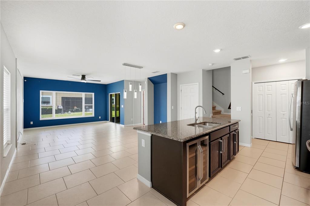 A kitchen island with a wine cooler sits in front of a blue-walled living area — 1617 MOHEGAN BOULEVARD, KISSIMMEE, FL