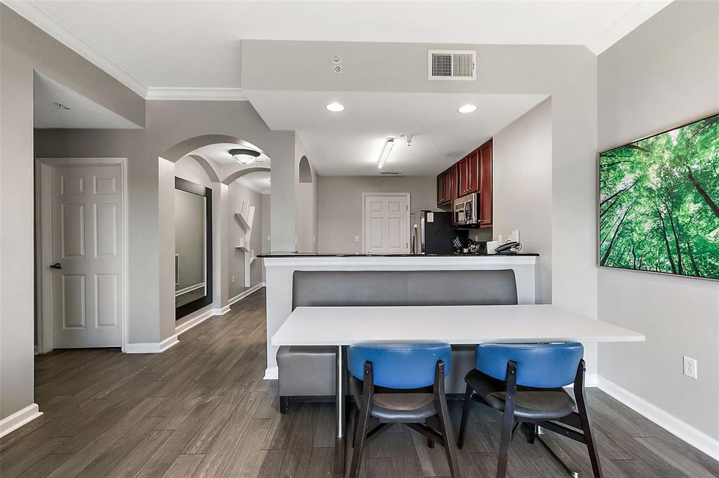 A dining area with a bench and two blue chairs sits before a kitchen counter — 14501 GROVE RESORT AVENUE UNIT 1614, WINTER GARDEN, FL