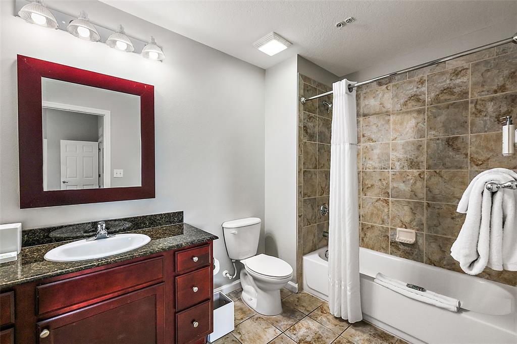 A bathroom features a dark wood vanity, granite countertop, toilet, and a tiled shower-tub combo — 14501 GROVE RESORT AVENUE UNIT 1614, WINTER GARDEN, FL