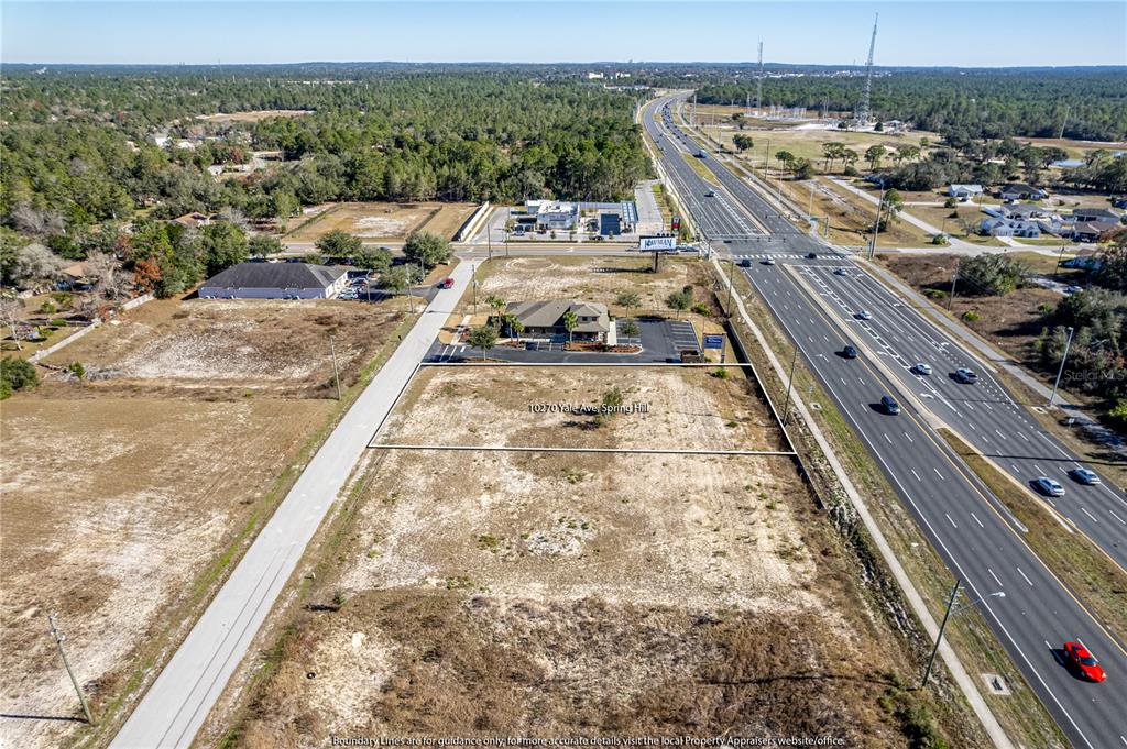 An aerial view shows a vacant rectangular lot adjacent to a road and highway — 10270 YALE AVENUE, WEEKI WACHEE, FL