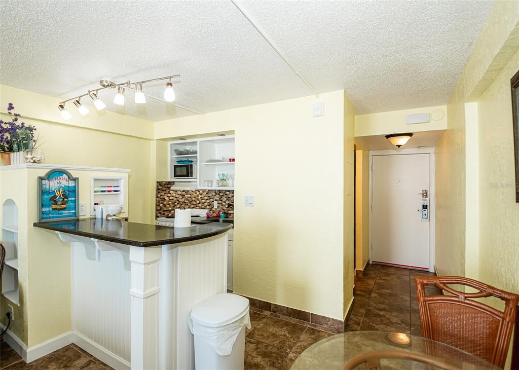 A kitchen with a breakfast bar, tile flooring, and a white door in the background — 2301 S ATLANTIC AVENUE UNIT 435, DAYTONA BEACH, FL