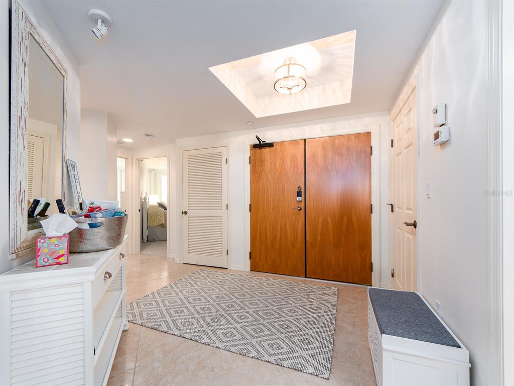 An entryway features double wood doors, a patterned area rug, and a recessed ceiling light — 1370 GULF BOULEVARD UNIT 204, CLEARWATER, FL