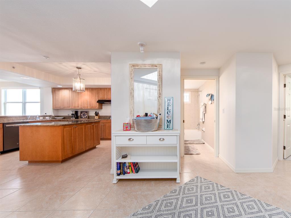 A white console table sits in a hallway between a kitchen and a bathroom — 1370 GULF BOULEVARD UNIT 204, CLEARWATER, FL
