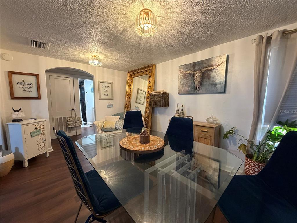 A dining room features a glass table, blue chairs, a large gold mirror, and artwork — 2425 SE 10TH AVENUE, GAINESVILLE, FL