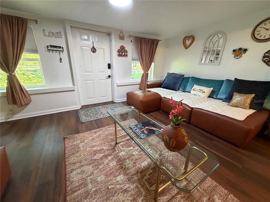 A living room features a brown leather sectional, a glass coffee table, and wood-look flooring — 2425 SE 10TH AVENUE, GAINESVILLE, FL