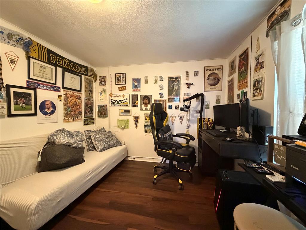 A bedroom features a white sofa, a gaming chair, and a desk with computer monitors — 2425 SE 10TH AVENUE, GAINESVILLE, FL