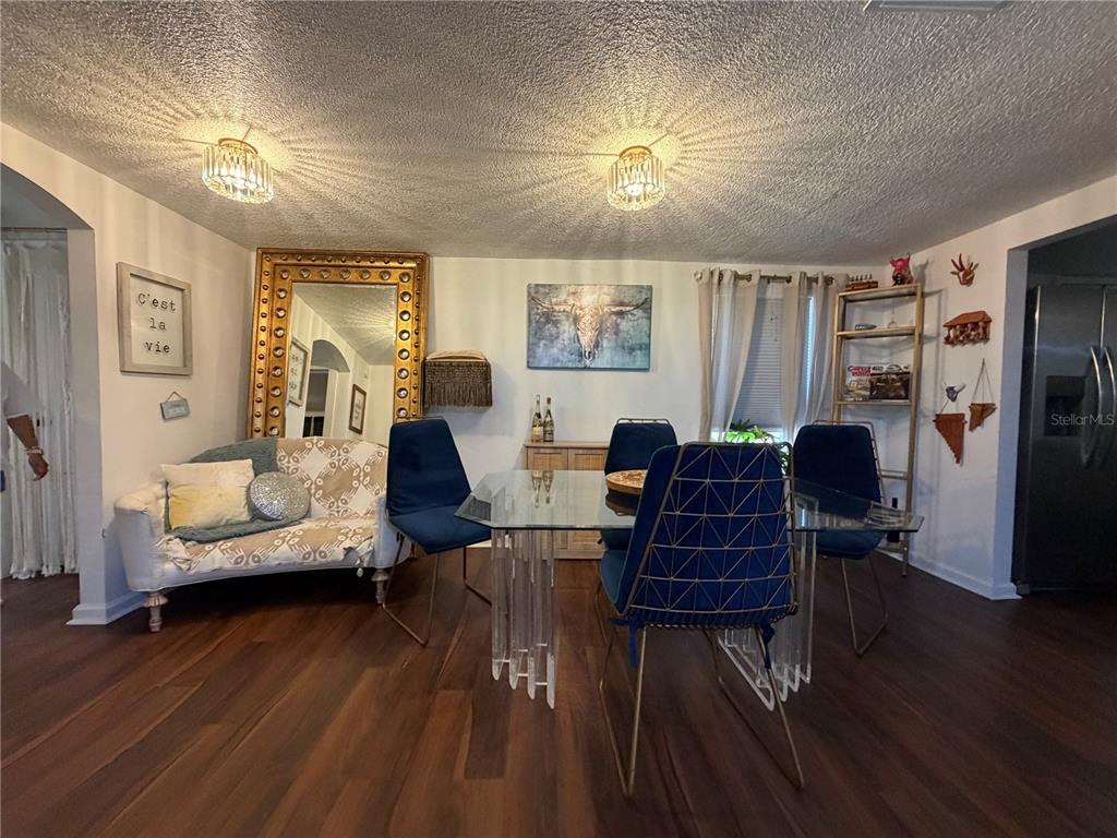 A dining room features a glass table with blue chairs, a sofa, and a large mirror — 2425 SE 10TH AVENUE, GAINESVILLE, FL