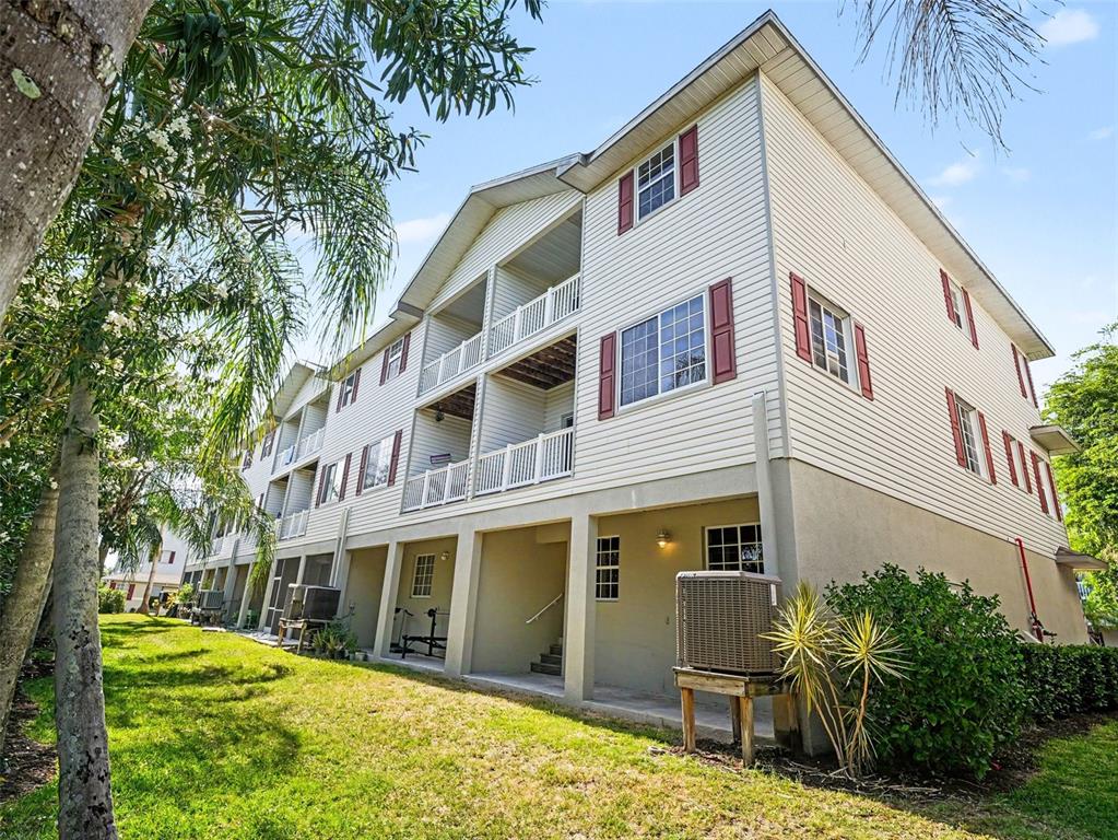 A multi-story apartment building with beige siding, red shutters, and ground-level parking — 3325 10TH LANE W, PALMETTO, FL