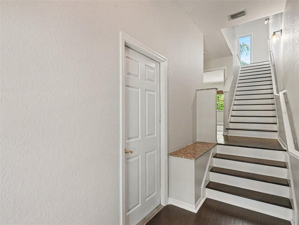 A white door stands next to a staircase with dark treads and a granite-topped ledge — 3325 10TH LANE W, PALMETTO, FL