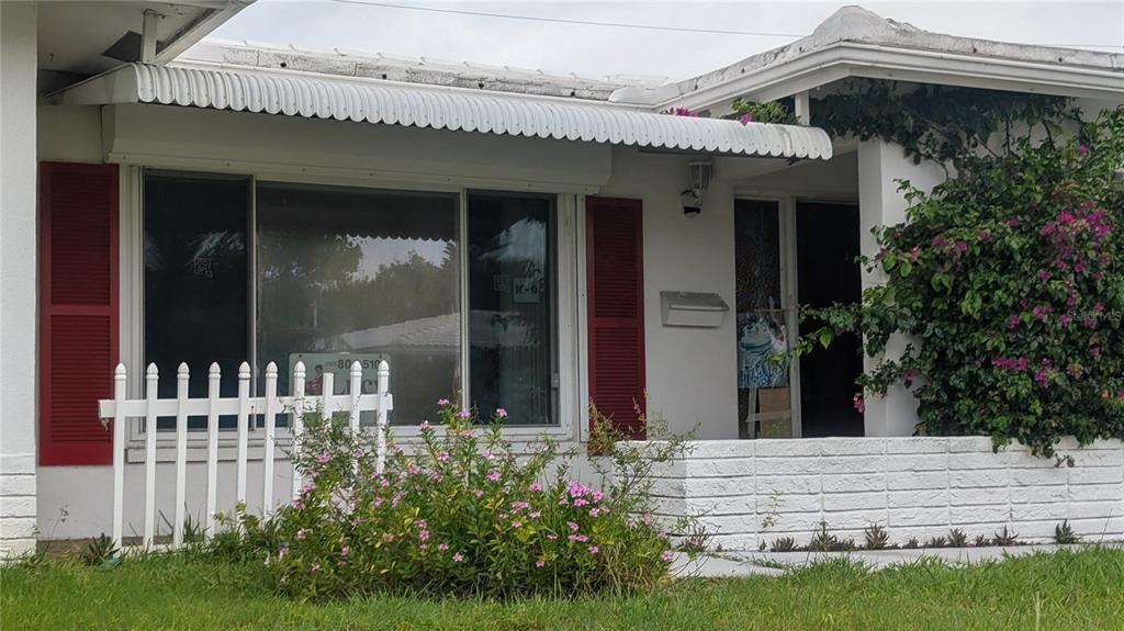 A white house exterior features a small front porch, red shutters, and a white fence — 9640 45TH STREET N, PINELLAS PARK, FL