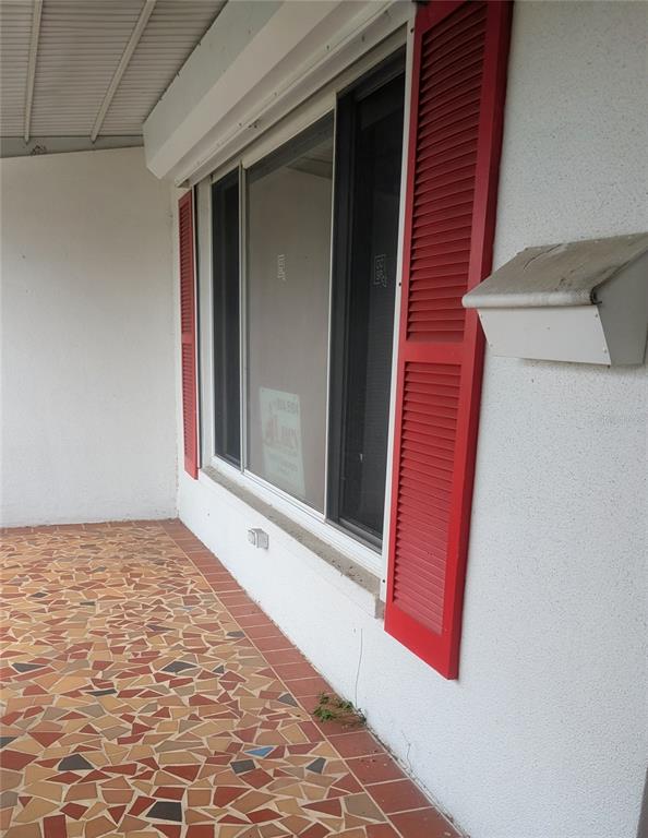 A covered porch features a mosaic tile floor, a large window with red shutters, and a mailbox — 9640 45TH STREET N, PINELLAS PARK, FL