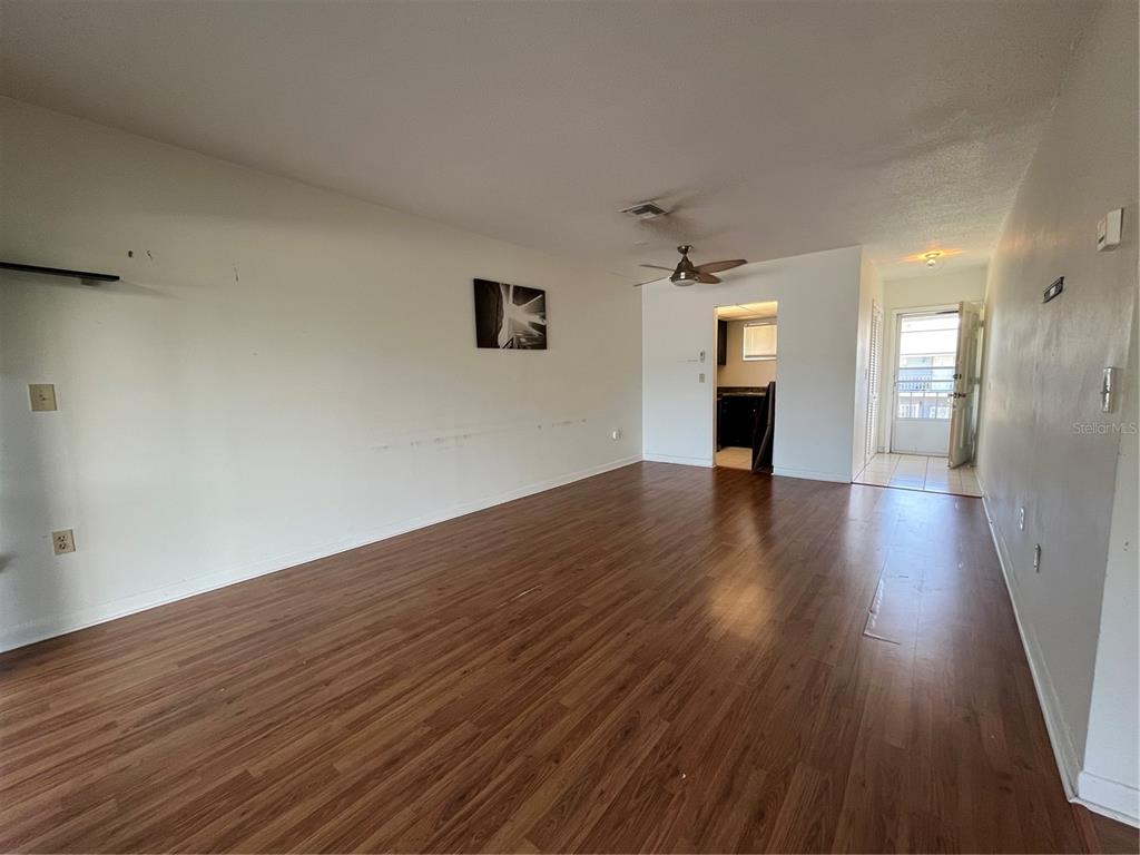 An empty living room features wood-look flooring, white walls, a ceiling fan, and a doorway — 1014 E SOUTH STREET UNIT 16, ORLANDO, FL