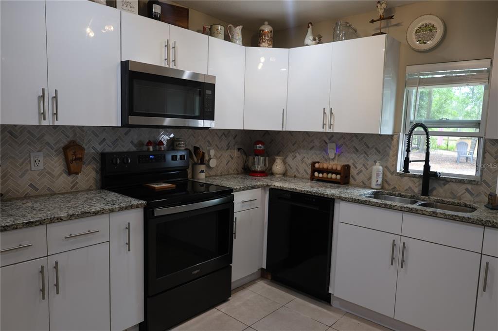 A white house sits on a large, sandy, tree-filled lot with several parked vehicles — 11927 FOXFIRE DR, HUDSON, FL